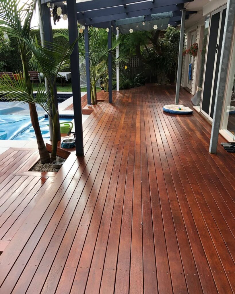 Merbau timber poolside decking with pergola and tropical plants in Bayside.